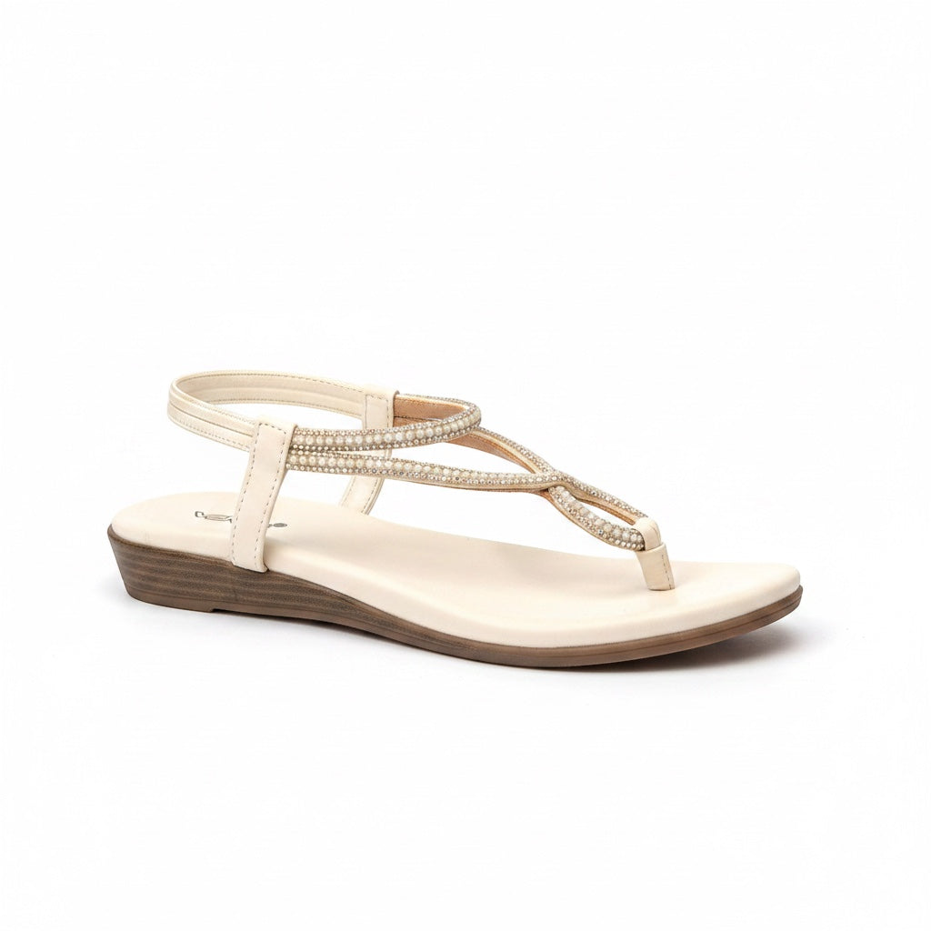 A single women's wedge sandal in a light cream or off-white color, featuring a platform sole, a thin toe strap, and a wrap-around ankle strap embellished with small rhinestones. The brand name 'Cosslett' is partially visible on the insole.